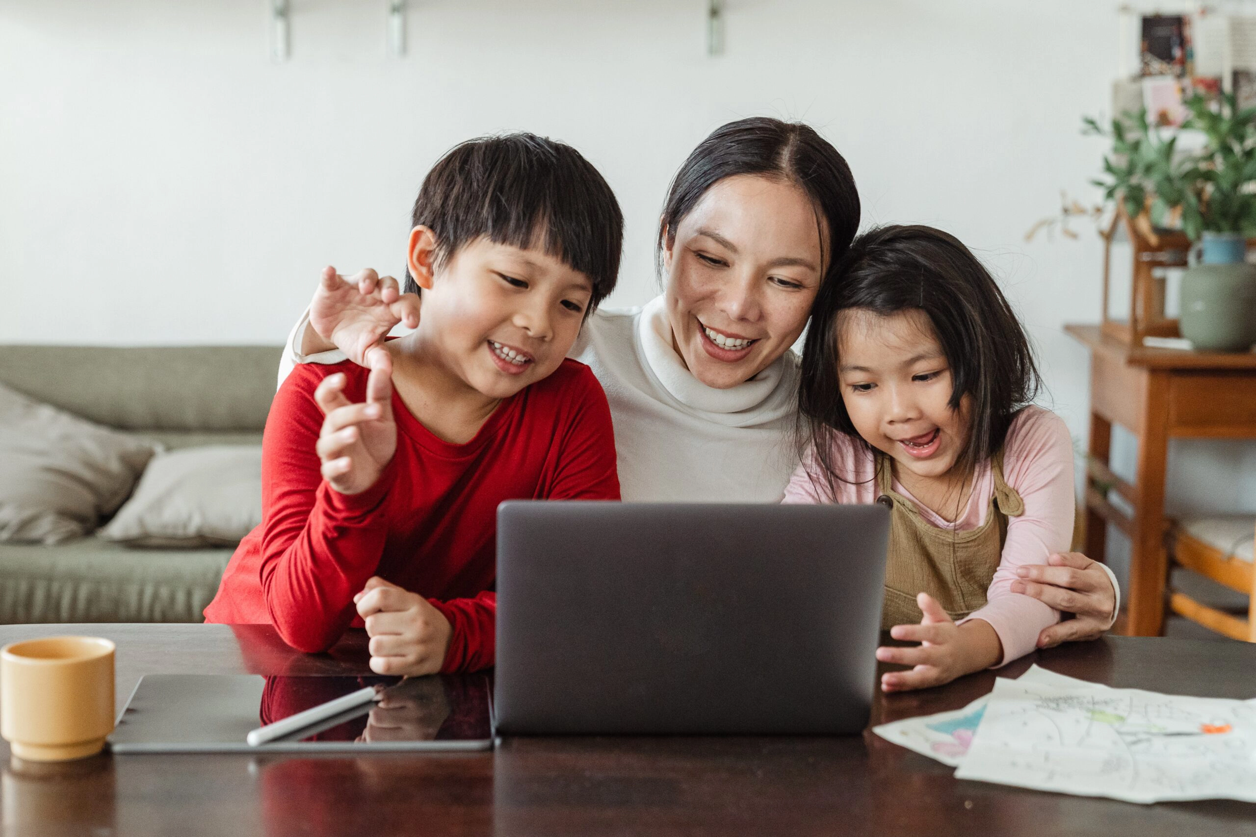 mother and two children smiling looking at laptop screen in home