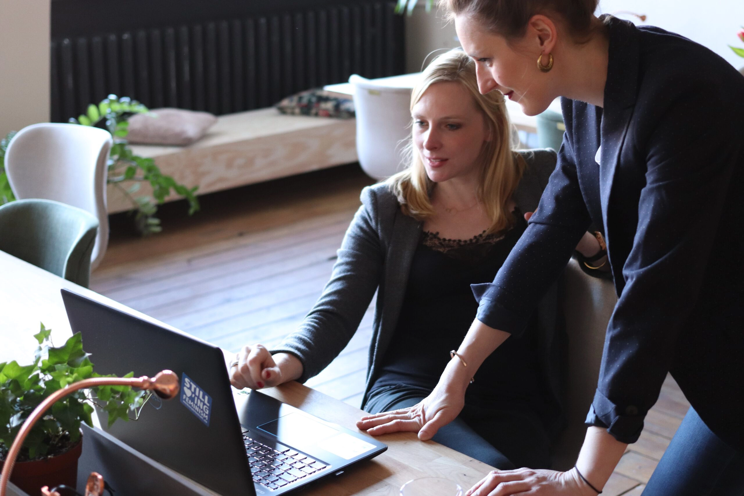 two professionally dressed women looking at laptop screen