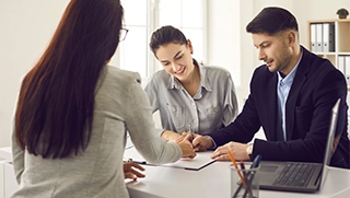 man and woman smiling at paperwork in office setting with insurance professional man and woman smiling at paperwork in office setting with insurance professional