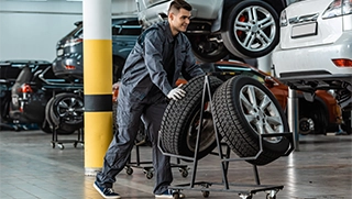 mechanic pushing tires through car repair shop