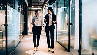 two white women dressed professionally in insurance office setting walking and talking two white women dressed professionally in insurance office setting walking and talking