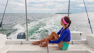 woman sitting on back edge of boat with fishing poles on the water in Florida