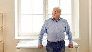 older business owner with white hair wearing jeans and button down in bright office space