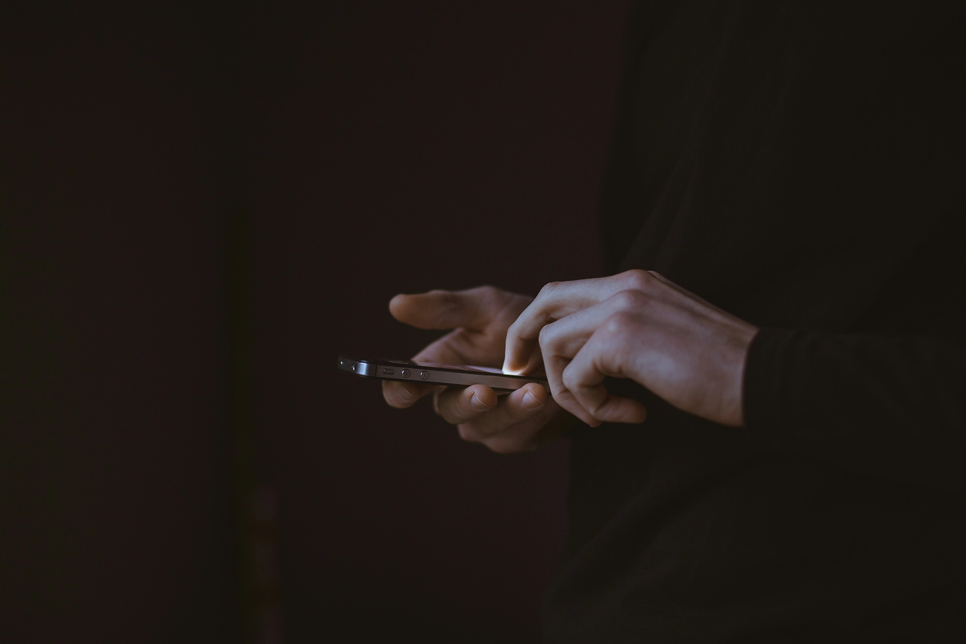 person holding phone against dark background