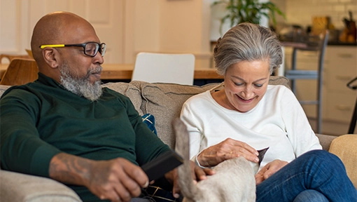 older couple siting on couch petting cat