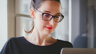 woman wearing glasses looking at mobile home insurance policy on laptop