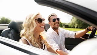 woman and man smiling driving insured convertible auto on sunny day woman and man smiling driving insured convertible auto on sunny day
