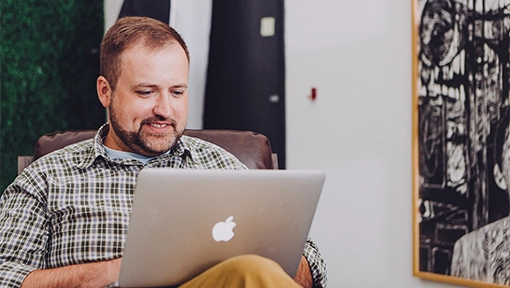 man on laptop in living room researching personal insurance lines
